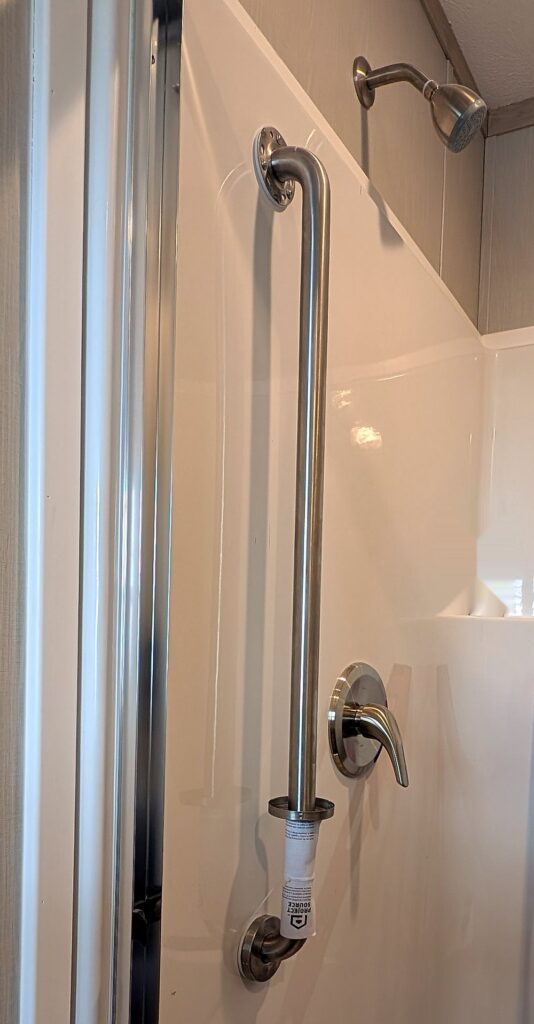 Stainless steel ADA grab bar installed in a new home shower