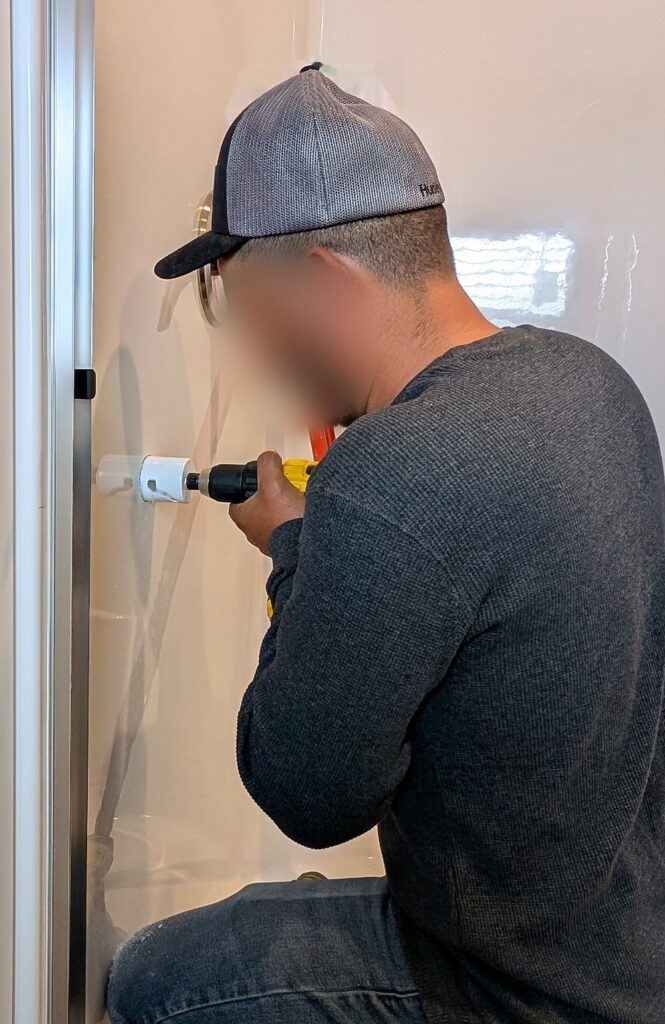 Installer drilling for ADA grab bars in a new home shower